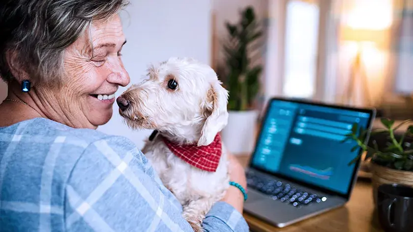 Senior woman holds dog in lap at home