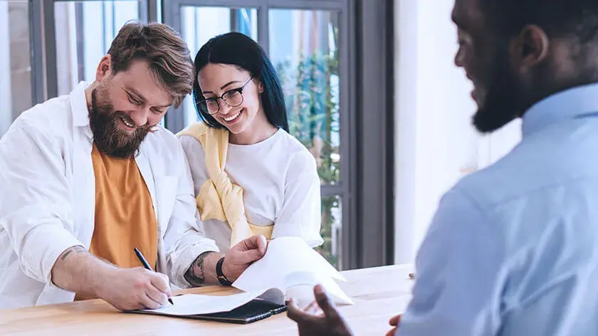 smiling-man-woman-signing-paperwork-with-agent