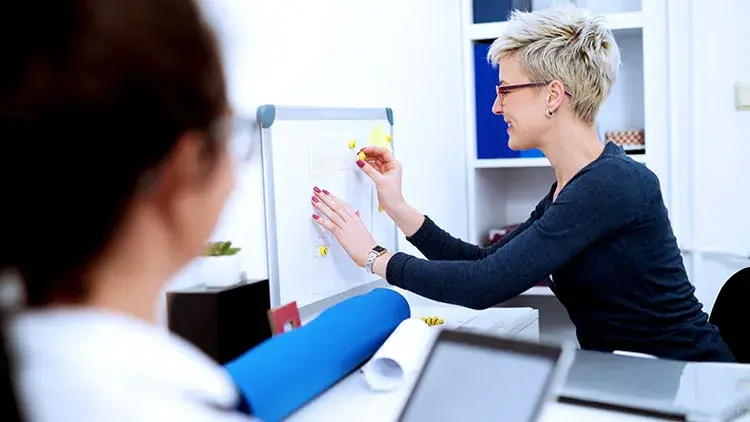 Two women whiteboard notes