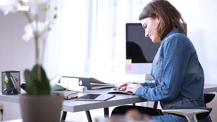 Woman at desk using calculator