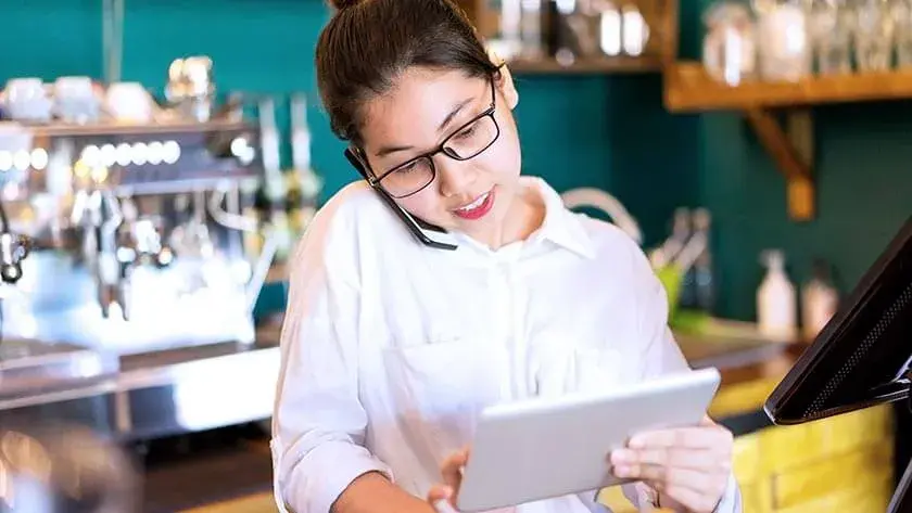 woman-on-phone-using-ipad-in-restaurant