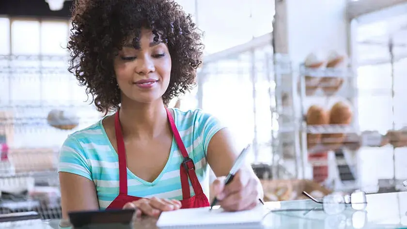 woman-writing-in-notebook-cafe standing at the counter 