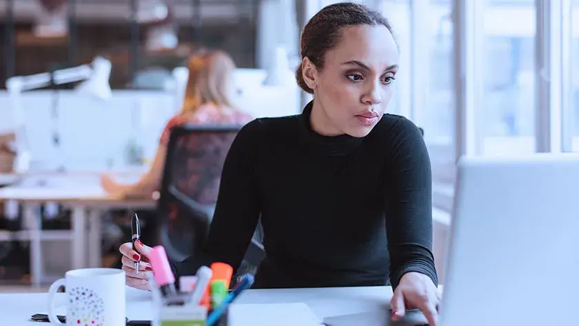 woman-writing-looking-at-laptop-at-office 1