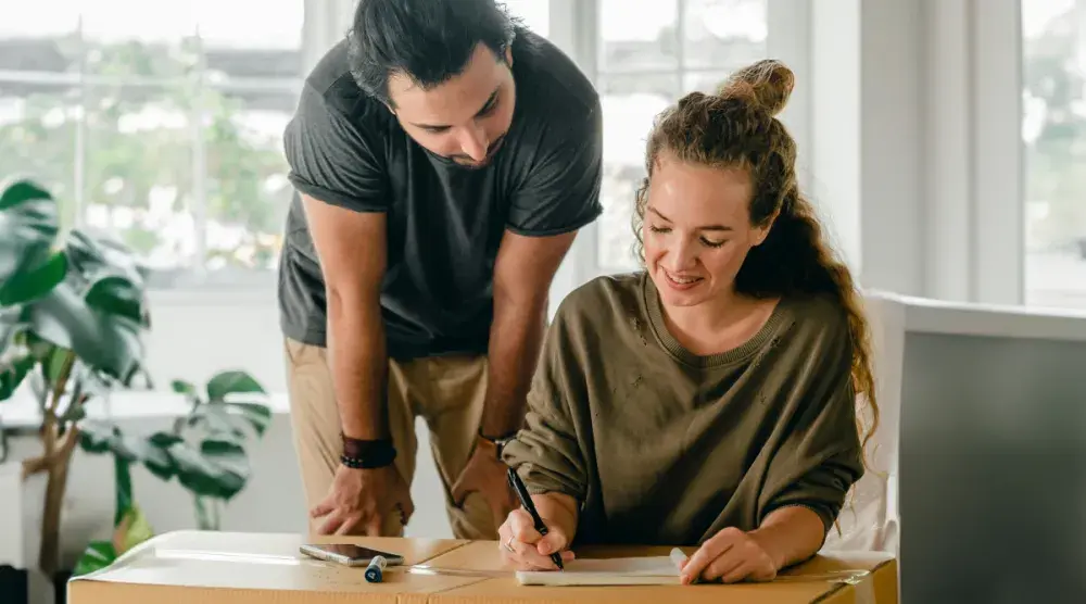 A man and woman look over loan documents to buy a house. Both a mortgage and a deed of trust serve similar purposes. Learn which may be right for you when buying a home.