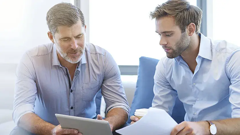 2 men in blue shirts looking at paperwork