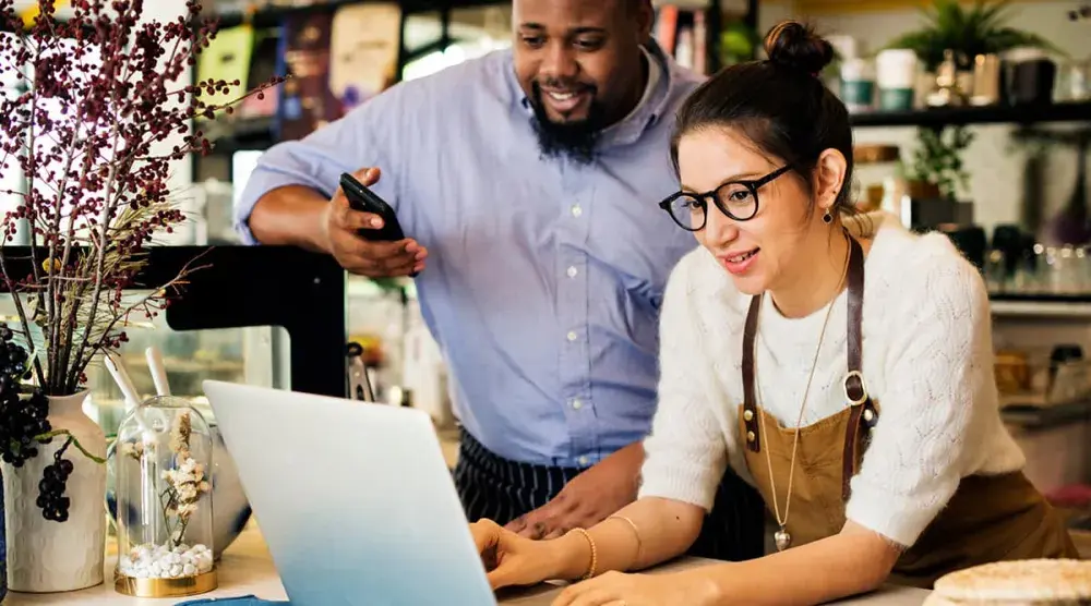 A woman and a man look at a laptop computer. All business owners should find out if they need to fill out a beneficial ownership report.