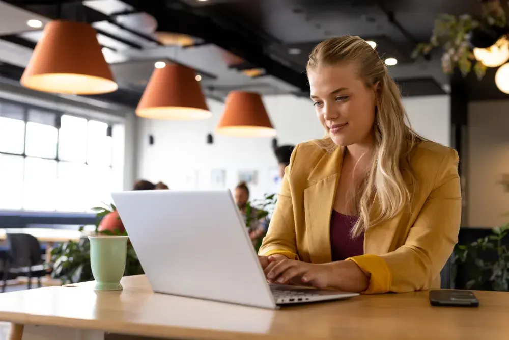 A woman sits at a table with an open laptop, searching for how to find tax deductions for consultants