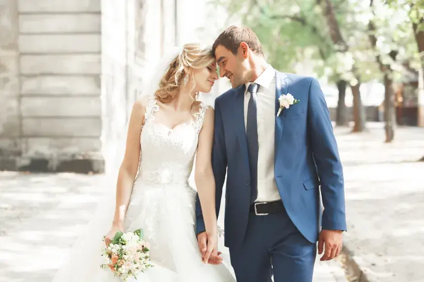 A woman and a man dressed in traditional wedding attire hold hands and press their foreheads together. A California written prenuptial agreement needs to meet the state’s legal requirements. 