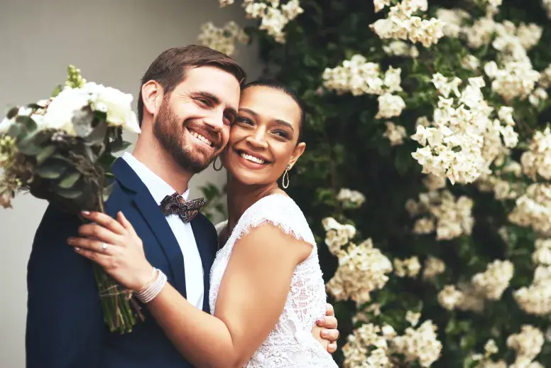 A man and woman wearing traditional wedding attire embrace outside the church after the ceremony. Having a prenuptial agreement in place can help give both parties peace of mind.