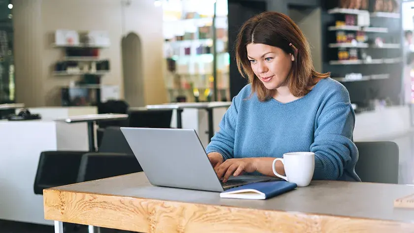 A woman sits at a table typing on her laptop computer as she works on an amended tax return.