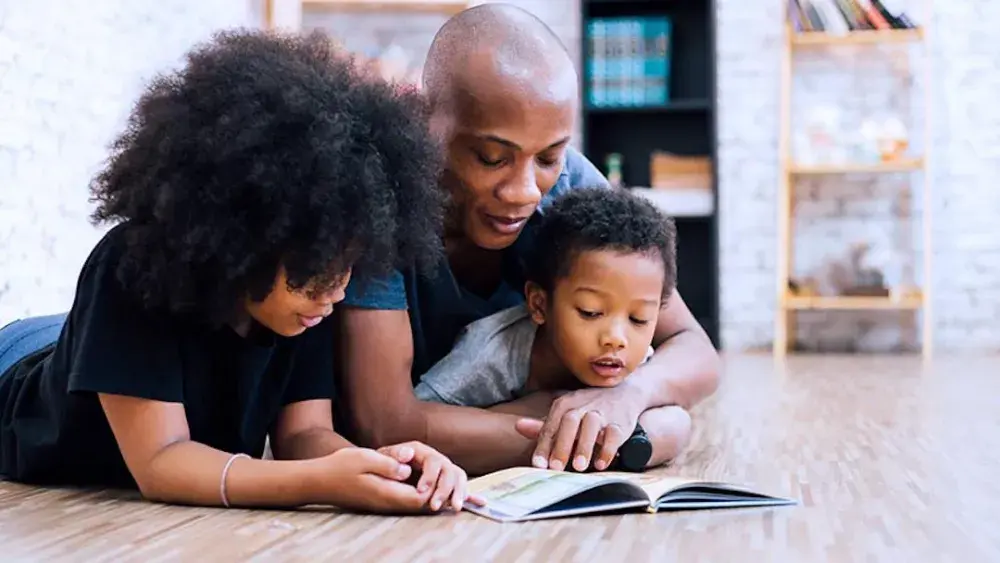 A parents plays with two children on the floor of their home. A Texas living trust allows you to specify how assets are distributed over time, thereby offering enduring financial security for your family. 