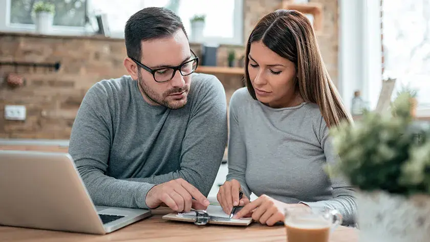 Couple sits side by side going over paperwork