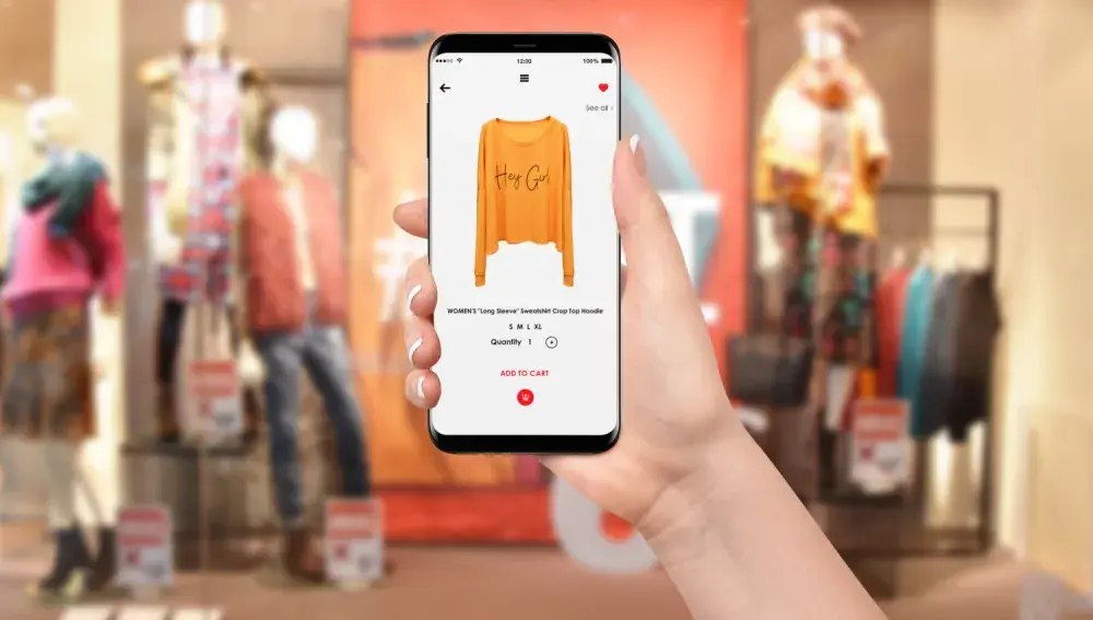 A person holds a smartphone open to a page that sells sweaters. The fast-growing trend of e-commerce can help business owners.