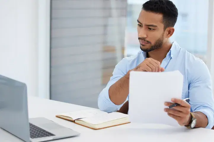 A small business owner holds paperwork while applying for an EIN online.