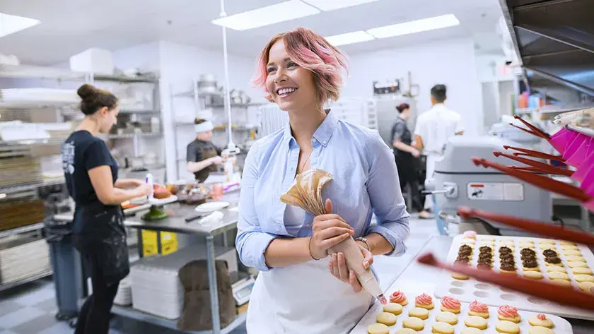 baker-in-restaurant-kitchen-holding-icing-piping