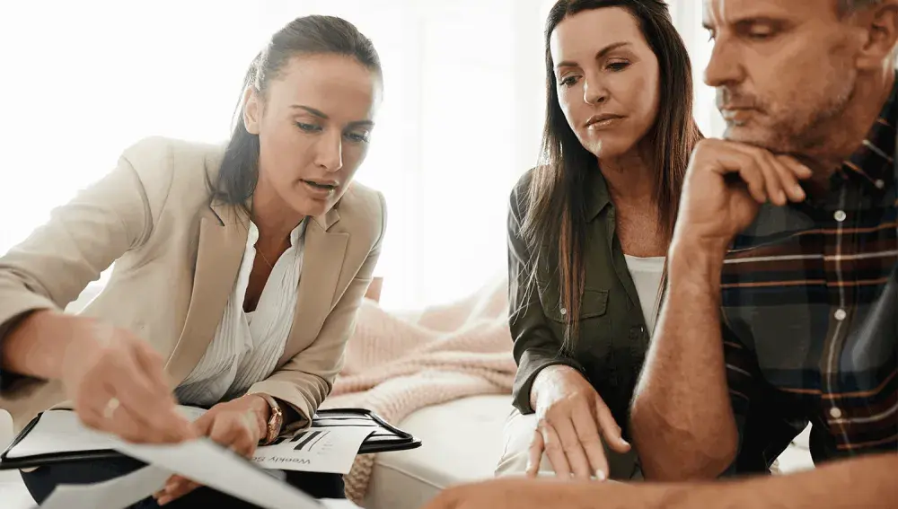 A woman explains some paperwork to another woman and a man.