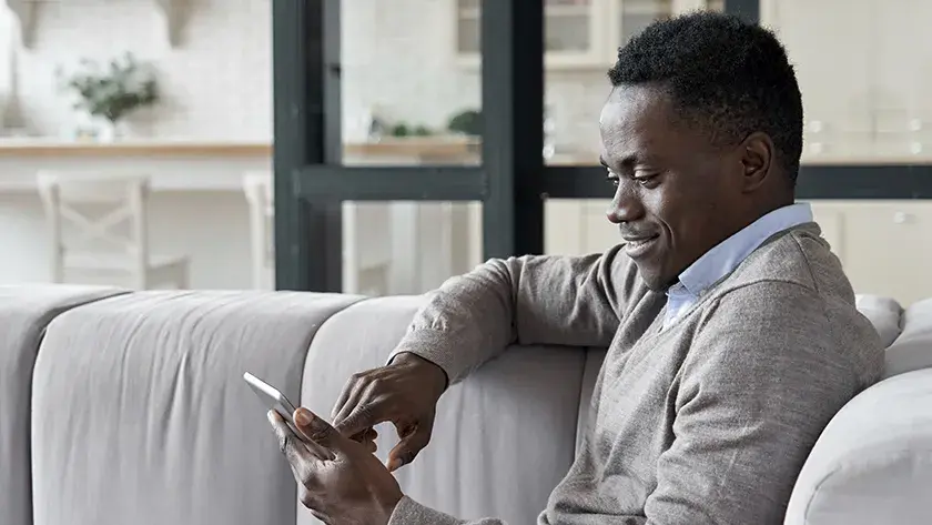 man in grey sweater playing on his phone 