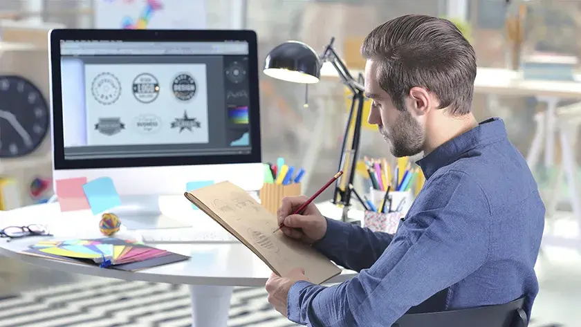 man sitting at a table working on a design 