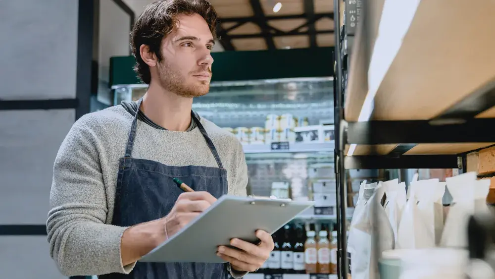 man wearing apron taking inventory 