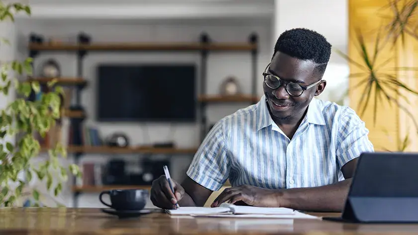 man writing in notebook in his home office 