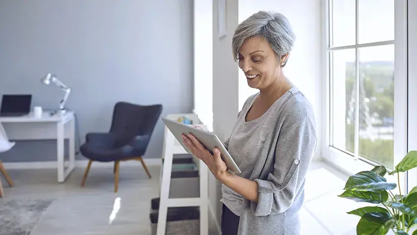 senior-woman-smiles-looking-at-ipad