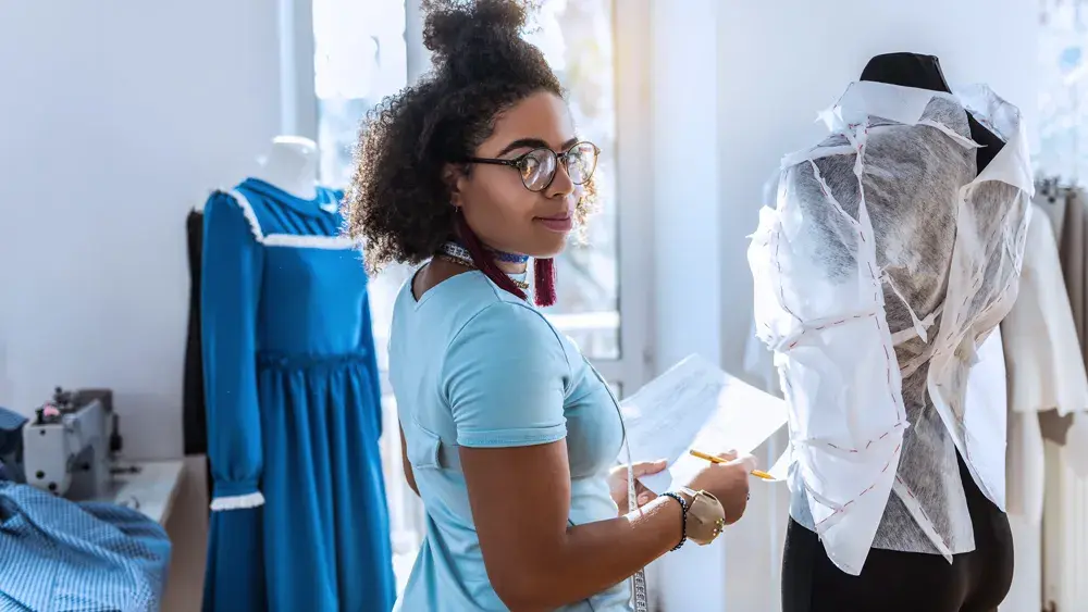 woman in blue shirt working with dress forms 