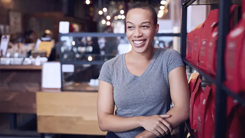 woman in grey shirt in front of shelves of coffee