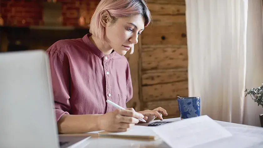 woman in pink shirt doing the books in her home office 