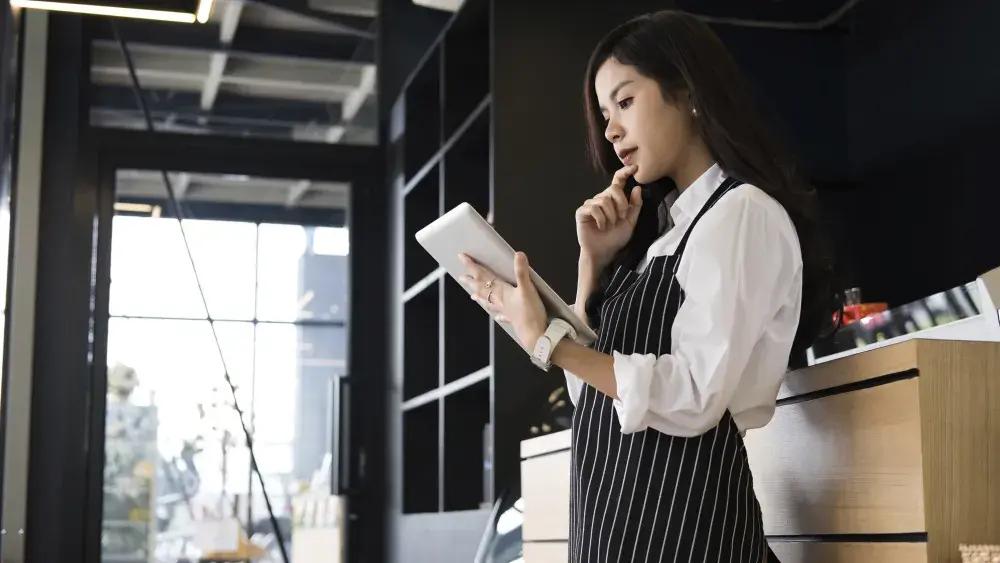 woman in striped apron looking at tablet