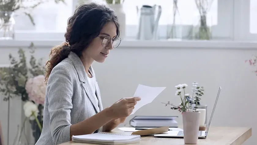 woman in striped jacket reading paperwork in her office