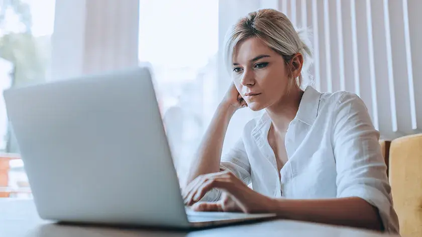 woman in white button up shirt working on her laptop