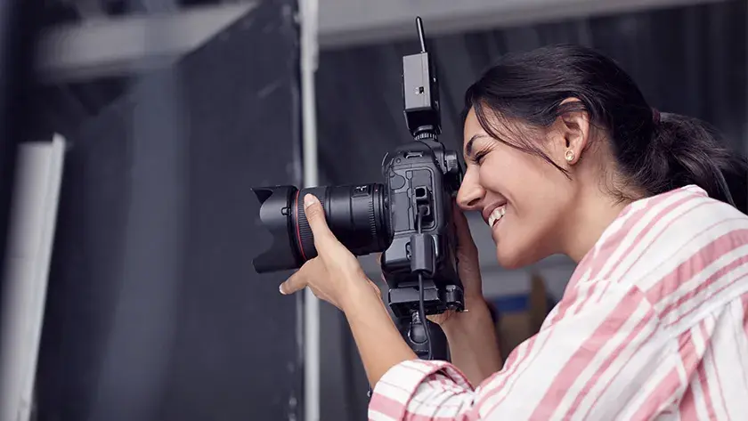 woman taking pictures with DSLR camera wearing pink striped shirt 