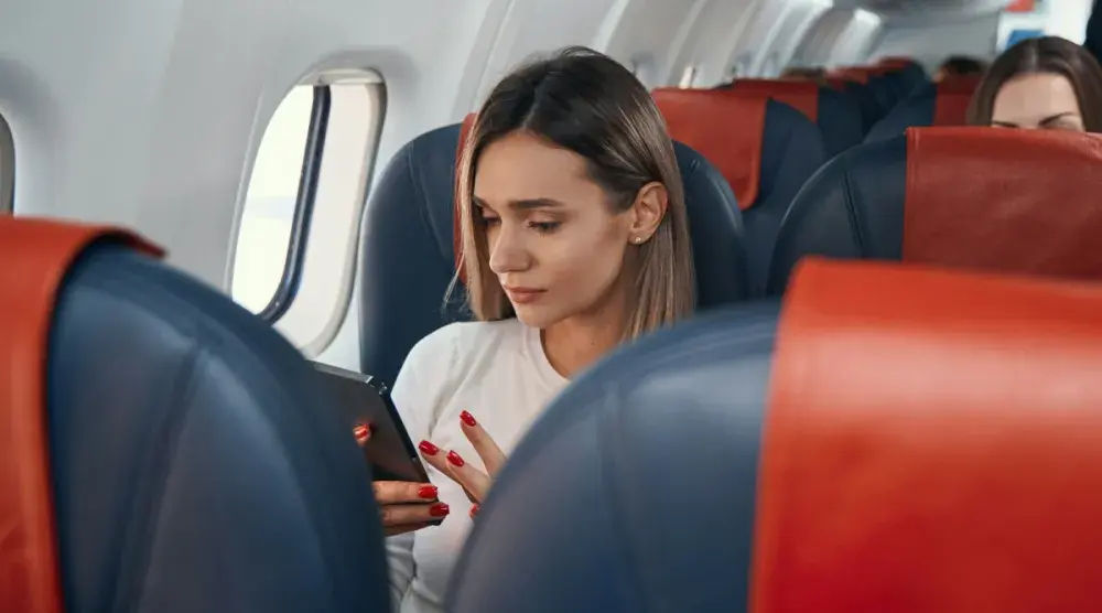 A woman on an airplane is seated next to a window and looks at her cellphone. When looking for an aviation accident attorney, consider finding one who specializes in the specific circumstances of the accident. 