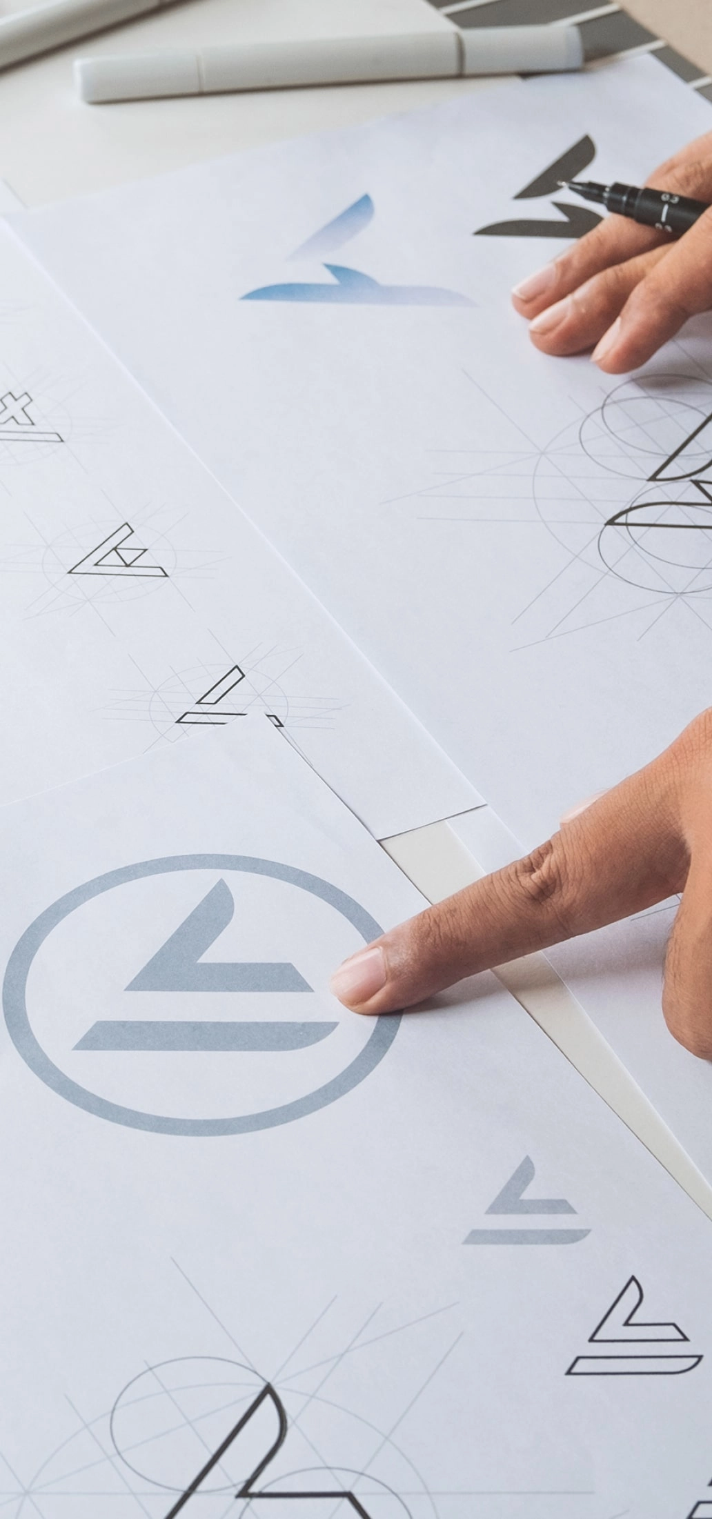 person pointing at piece of paper with different logo designs 