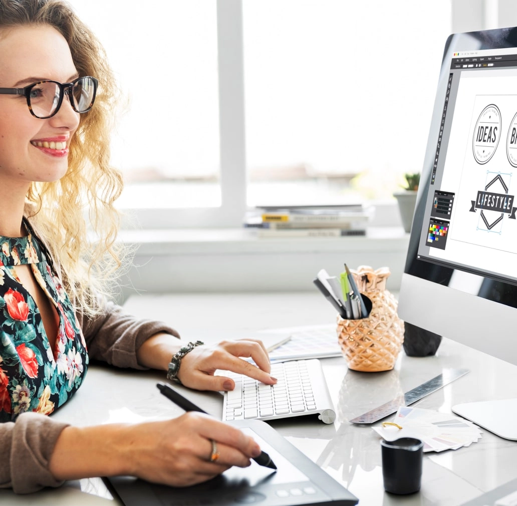 Woman in a floral shirt typing on keyboard and drawing on tablet